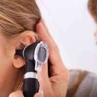 Close-up Of Doctor Checking Happy Girl's Ear With Otoscope